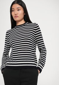 Maglione a righe blu navy e bianco, con collo a giro e maniche lunghe. Texture lavorata a maglia con polsini e orlo a coste.