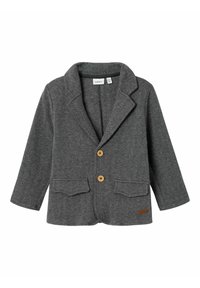Šedý herringbone blazer s klopovým límcem, dvěma předními kapsami a dřevěnými knoflíky. Obsahuje dlouhé rukávy a texturovanou látku.