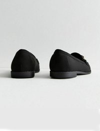 Zapatos de tela negros con un perfil bajo, punta redondeada y suela de goma plana. Presentan una textura suave y un diseño minimalista.