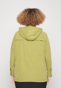 Giacca con cappuccio verde oliva, dal fit rilassato, con yoke posteriore, polsini con bottone e una texture del tessuto liscia.