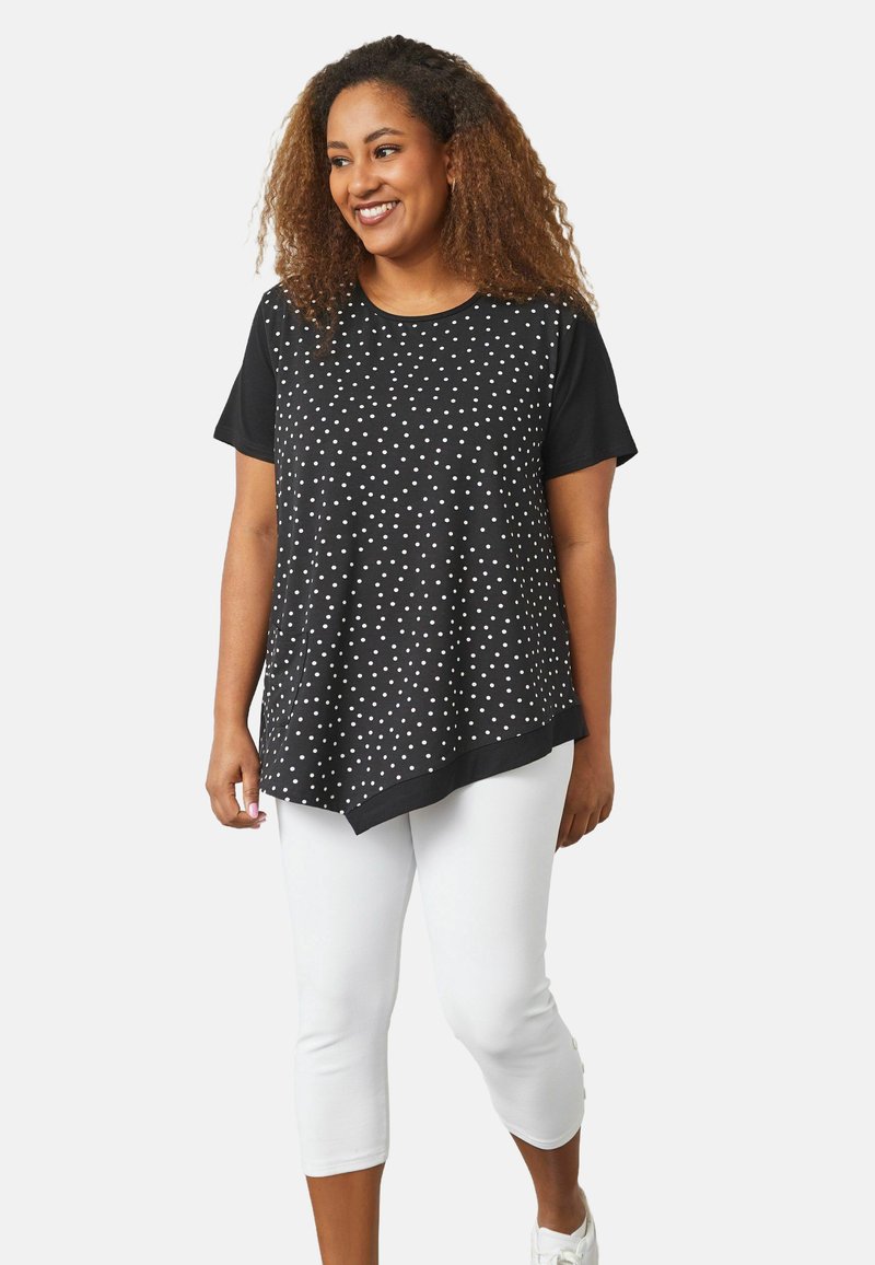 Top corto a maniche corte bianco e nero con motivo a pois, abbinato a pantaloni bianchi a vita alta. Tessuto morbido e design morbido.