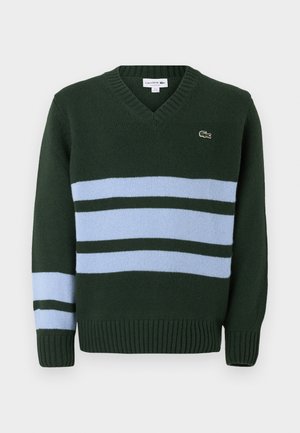 Grønn v-hals genser laget av strikket stoff, med lyseblå og mørkegrønne horisontale striper, og ribbestrikkede mansjetter og nederkant. Lacoste-logo på brystet.