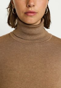 Maglione a collo alto marrone con texture a coste. Presenta un collo alto e un design aderente. Costruzione semplice e senza cuciture.