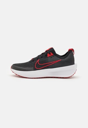 Černá sportovní bota s texturovaným svrškem, červenými akcenty, tkaničkami a logem. Obsahuje bílou mezisole a červenou podrážku pro lepší grip.