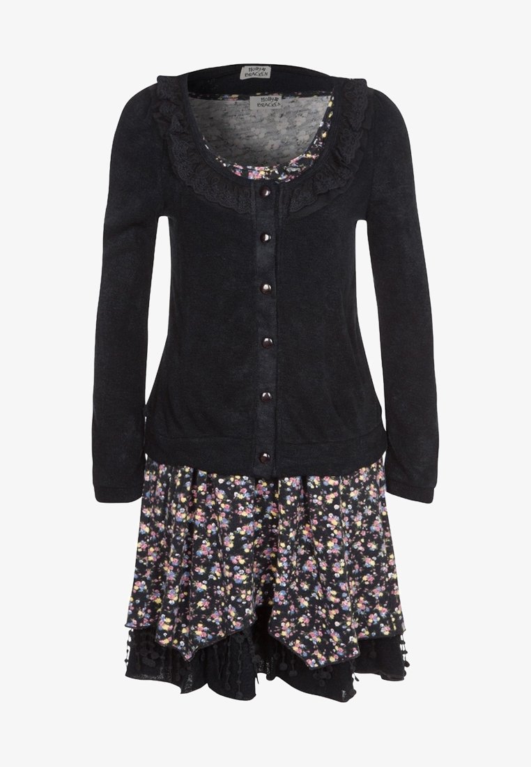Cardigan noir à manches longues avec un col à volants, porté sur une robe à volants à motifs floraux multicolores.