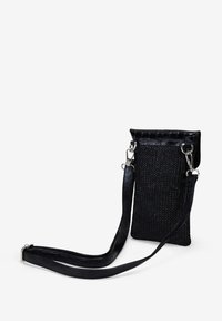 Bolso cruzado negro de tejido con un acabado texturizado, herrajes de plata y una correa delgada. Presenta un diseño de tapa plegable y forma rectangular.