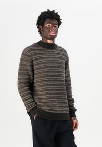 Maglione lavorato a maglia in marrone con strisce orizzontali texture. Presenta un collo e polsini a coste, una vestibilità rilassata e una finitura liscia e morbida.