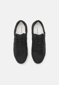Sneakers neri con una texture liscia, dotati di una punta arrotondata, design con lacci e suola in gomma bianca. Logo del brand visibile all'interno.