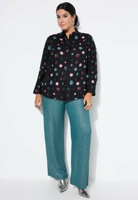 Svart knapp-up skjorta med färgglada cirkulära mönster. Matcher med turkosa, skimrande vida byxor och silverfärgade klackar med spetsig tå.