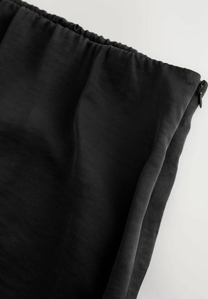 Černá, lehká tkanina s hladkým povrchem, s nařaseným pasem a bočním zipem. Jednoduchý design bez dalších vzorů.