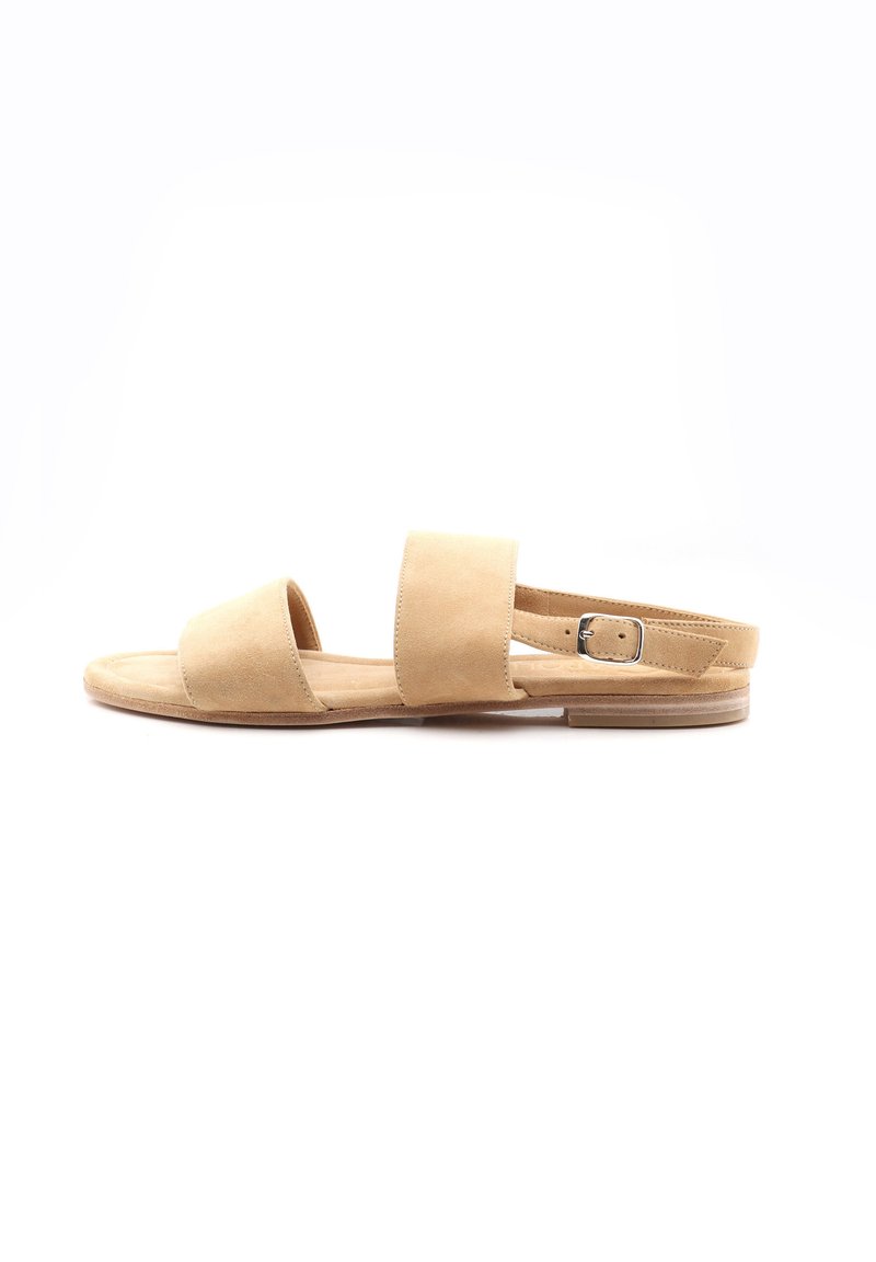 Tan suede sandaalit litteällä pohjalla, joissa on kaksi leveää jalkahihnaa ja säädettävä nilkkahihna. Minimalistinen muotoilu ilman koristeita.