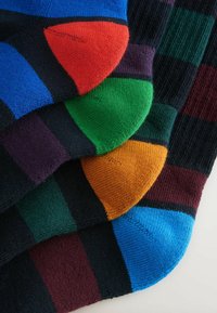 Multikleuren sokken met blauwe, rode, groene, paarse en oranje accenten. Gemaakt van zachte stof met duidelijke gestreepte patronen en gekartelde manchetten.