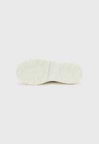 Suela de zapato de goma blanca con patrón texturizado, que presenta ranuras y logotipos, diseñada para proporcionar tracción y durabilidad. Acabado suave y diseño ligero.