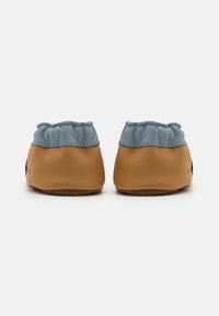 Chaussures en cuir marron et bleu avec une texture froncée au col et une semelle souple, dotées de bords cousus et d'une forme arrondie.