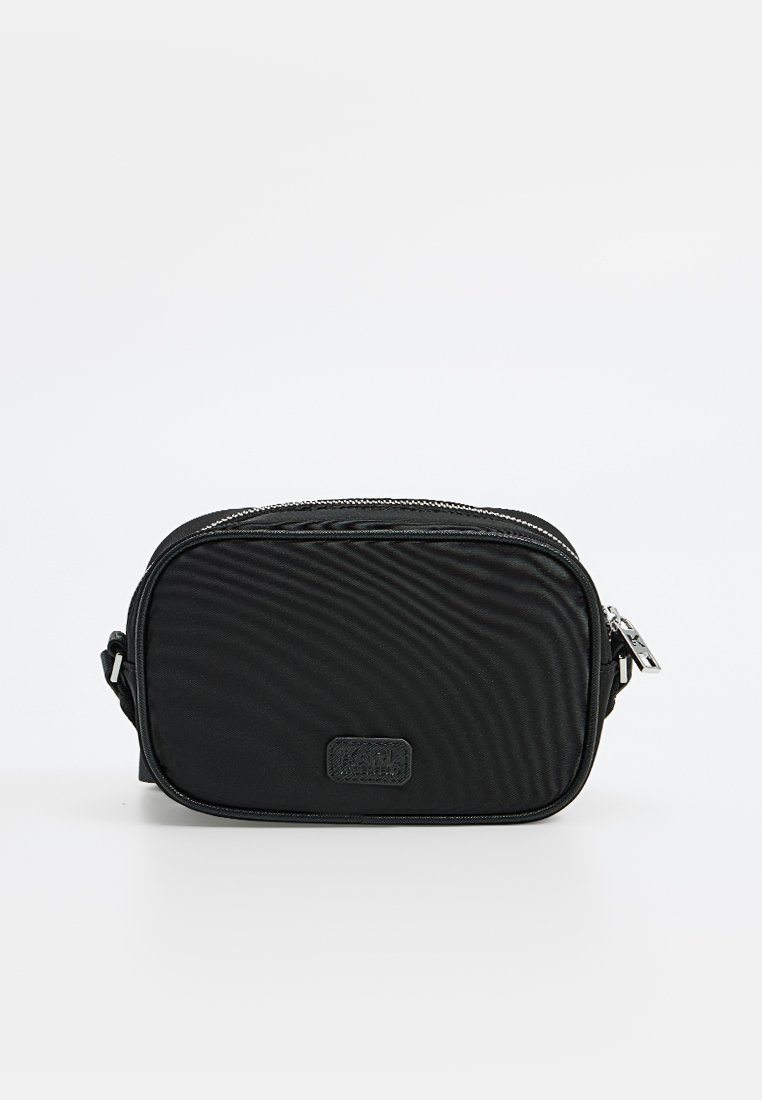 Bolso cruzado negro de nailon con forma rectangular, superficie texturizada, cierre de cremallera y un pequeño parche con el logo en la parte frontal. Incluye una correa ajustable.