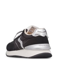 Black athletic shoe featuring suede and fabric materials. Silver accents on the heel and logo. Thick outsole with textured surface.