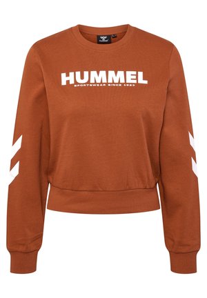 Sweat-shirt à manches longues couleur rouille avec texte blanc « HUMMEL SPORTSWEAR SINCE 1923 » sur la poitrine et bandes chevrons blanches sur les manches.