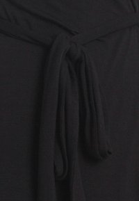 Schwarzes Stoffkleid mit einer geknoteten Taillendetail, das eine glatte Textur und einen fließenden Schnitt aufweist. Keine auffälligen Muster oder Hardware sichtbar.