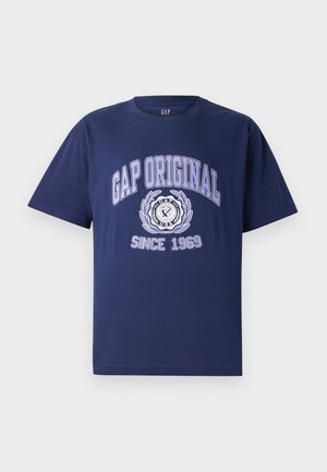 Camiseta de algodón azul marino de manga corta, con el texto y diseño gráfico "GAP ORIGINAL", emblema circular y "DESDE 1969" debajo.
