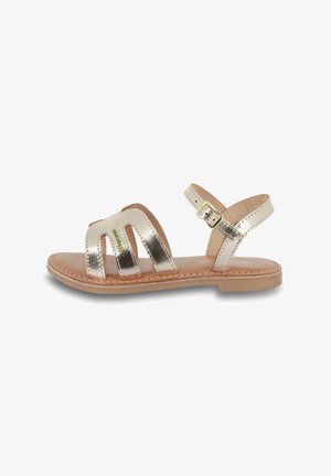 Metallische gouden sandalen hebben drie brede banden met uitsparingen, een achterste band met een gesp en een tan inlegzool op een platte zool.