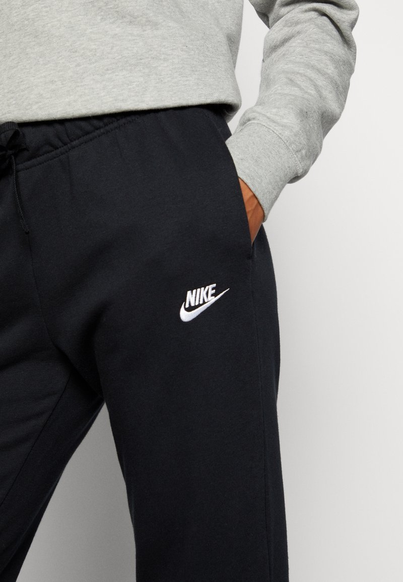 Pantalons de survêtement Nike en bleu marine foncé avec une coupe décontractée, présentant une taille élastique et un logo brodé blanc sur la cuisse gauche.