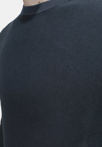 Maglione blu navy con un motivo a maglia testurizzato, scollatura a girocollo e un discreto dettaglio del logo sul petto.