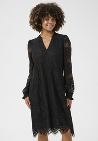 Black lace dress featuring long sheer sleeves, a V-neckline, a loose fit, and a scalloped hem with intricate circular patterns.