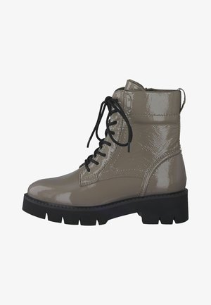 Bottines en cuir verni beige avec lacets noirs, semelle en caoutchouc épaisse et bout rond. Présente une texture brillante et des accents cousus.