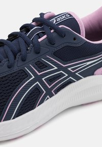 Baskets de sport bleu marine en mesh et matière synthétique, avec des accents roses, semelle blanche, et un logo distinctif sur la languette. Design élégant.