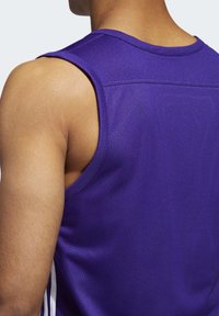 Homme portant un débardeur de sport violet, vu de dos, mettant en avant les détails des épaules et du haut du dos.