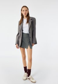 Grå blazer med store knapper, hvid polo shirt og en grå mini nederdel. Sæt sammen med cremefarvede sneakers og bordeaux ribbede strømper.