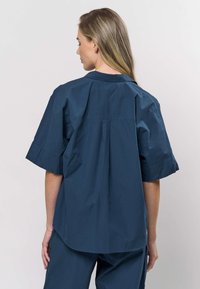 Mörkblå kortärmad skjorta i mjukt tyg med avslappnad passform, bakre veck och klassisk krage.