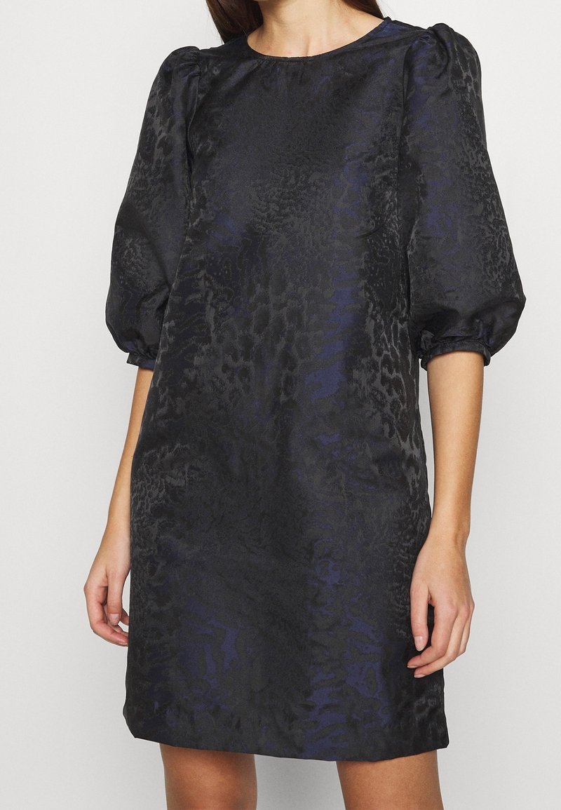 Černé šaty s texturovaným fialovým zvířecím vzorem, krátké nabírané rukávy, kulatý výstřih a volný střih, sahající nad kolena.