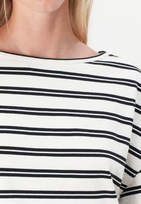 Stripet t-skjorte med svarte og hvite horisontale striper, vid hals og et mykt, lett stoff.