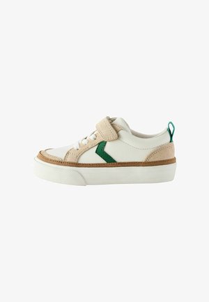 Baskets blanches en cuir avec des accents en suède beige, logo vert sur le côté et bande velcro ajustable. Semelle texturée avec un motif de grip.