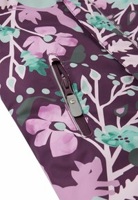Paars stoffen met een bloemenpatroon, met roze en groene bloemen; heeft een ritszak met een grijze trekker en een gladde textuur.