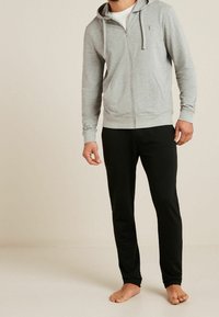 Gray zip-up hoodie with hood and drawstrings, paired with black pants. Soft fabric, fitted design, no visible patterns or logos.