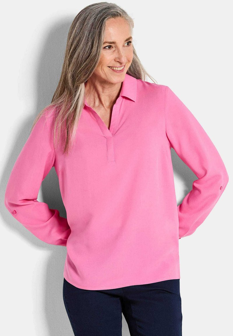 Langärmlige, pinke Bluse mit Kragen, ausgestattet mit einem V-Ausschnitt und Knopfdetails an den Ärmeln. Glatte Stoffqualität mit leicht glänzender Oberfläche.