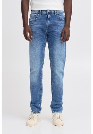 Blugi de culoare albastru deschis, din denim, cu cinci buzunare, croială dreaptă și ușoare decolorări pe coapse. Purtați cu adidași albi.