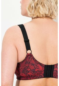 Roter und schwarzer Spitzen-BH mit einstellbaren schwarzen Trägern. Verfügt über einen Haken- und Ösenverschluss sowie dekorative Nähte am Band.
