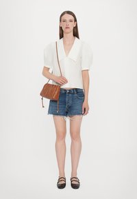 Vit kortärmad blus med en stor krage, ihopparad med slitna denimshorts. Brun läder crossover-väska med rynkdetaill. Svarta ballerinas.