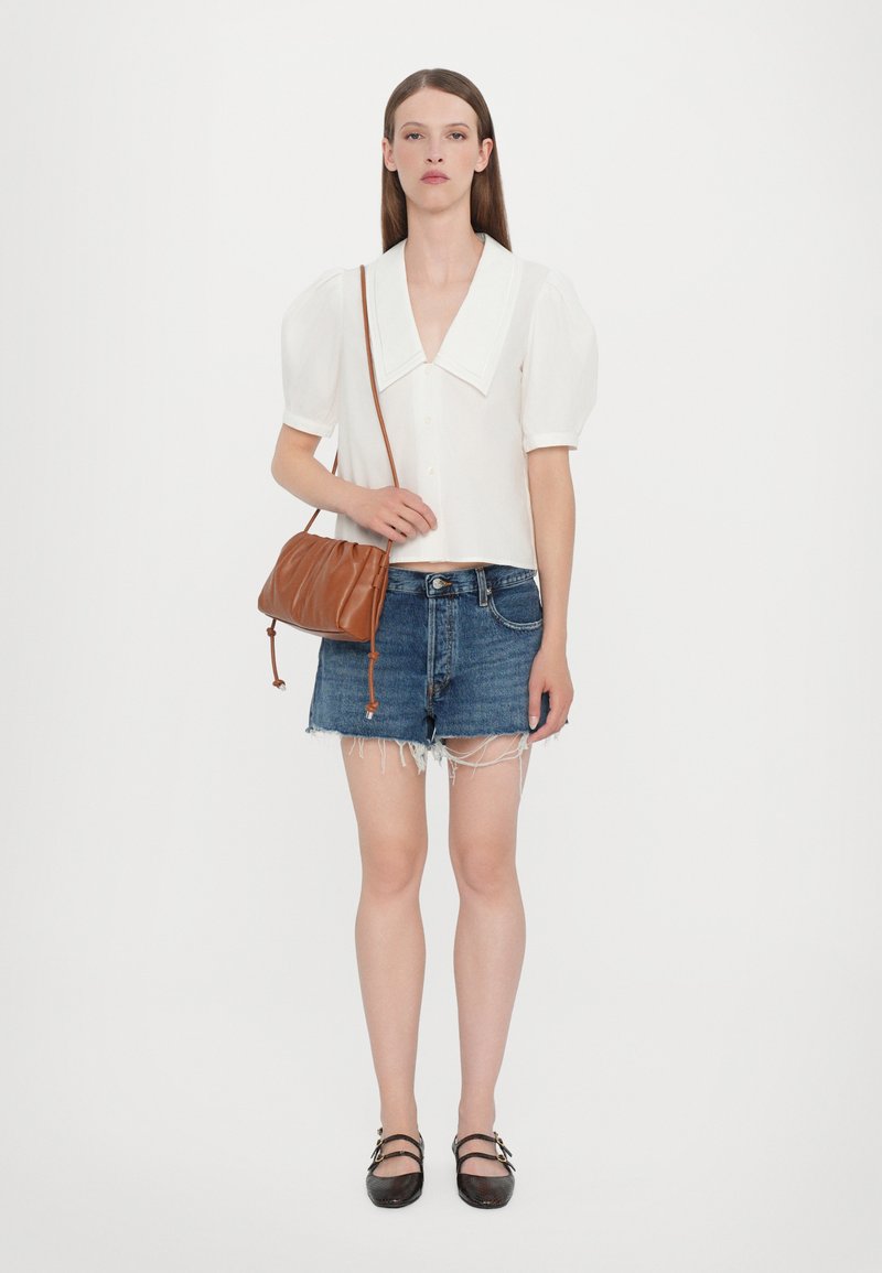 Vit kortärmad blus med en stor krage, ihopparad med slitna denimshorts. Brun läder crossover-väska med rynkdetaill. Svarta ballerinas.