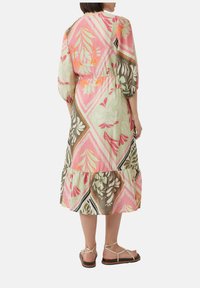 Sukienka w kwiatowy nadruk z warstwowym krojem, bufkami oraz wcięciem w talii. Kolory to różowy, zielony i brązowy, z lekkiego materiału.