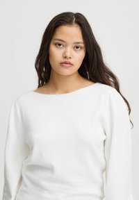 Weißer Pullover mit weitem Ausschnitt, strukturiertem Strickmaterial, langen Ärmeln und lockerer Passform. Glatte Oberfläche mit gerippten Details am Hals.