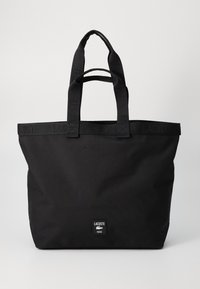 Borsa a tracolla nera Lacoste con doppi manici e dettaglio della tracolla con logo in rilievo, dotata di una piccola patta frontale con nome del marchio e icona del coccodrillo.