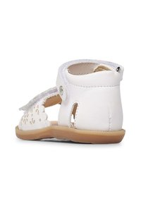 Sandalo bianco in pelle con design floreale perforato, cinturino regolabile e suola in gomma. Presenta un tacco arrotondato e una fodera morbida.