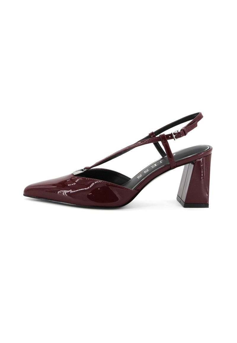 Décolleté in vernice bordeaux con punta a mandorla e tacco quadrato chunky. Presenta una sottile fascia regolabile.