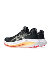 Baskets de sport noires avec un upper respirant, des accents réfléchissants, une semelle extérieure blanche et dégradée en jaune et rouge, et une technologie GEL.