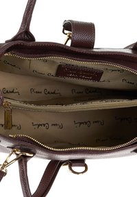Interno della borsa marrone in ecopelle con una texture liscia, scomparti con zip e una fodera beige che presenta il logo ripetuto "Pierre Cardin".