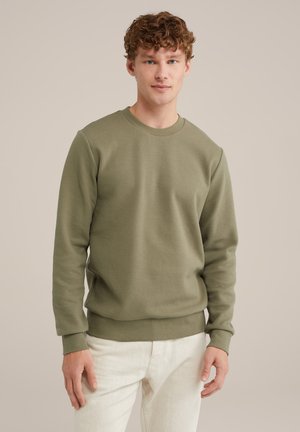 Olivgrön långärmad sweatshirt i textil med rundad halsringning. Har ribbade cuffs och fåll. Parat med ljusa byxor.